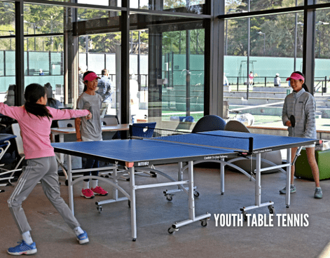 Youth table tennis players practicing indoors at the Goldman Tennis Center during a youth table tennis program through Lifetime Activities.
